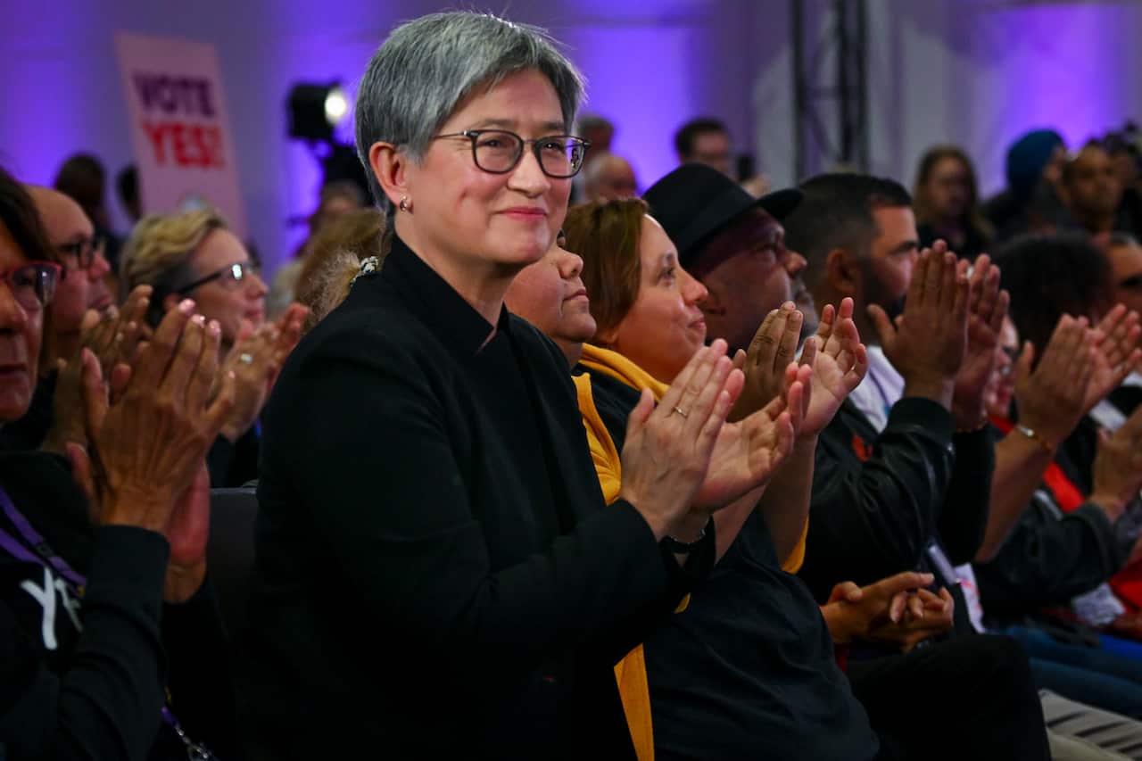 Penny Wong, wearing black, among a group of people standing and applauding 