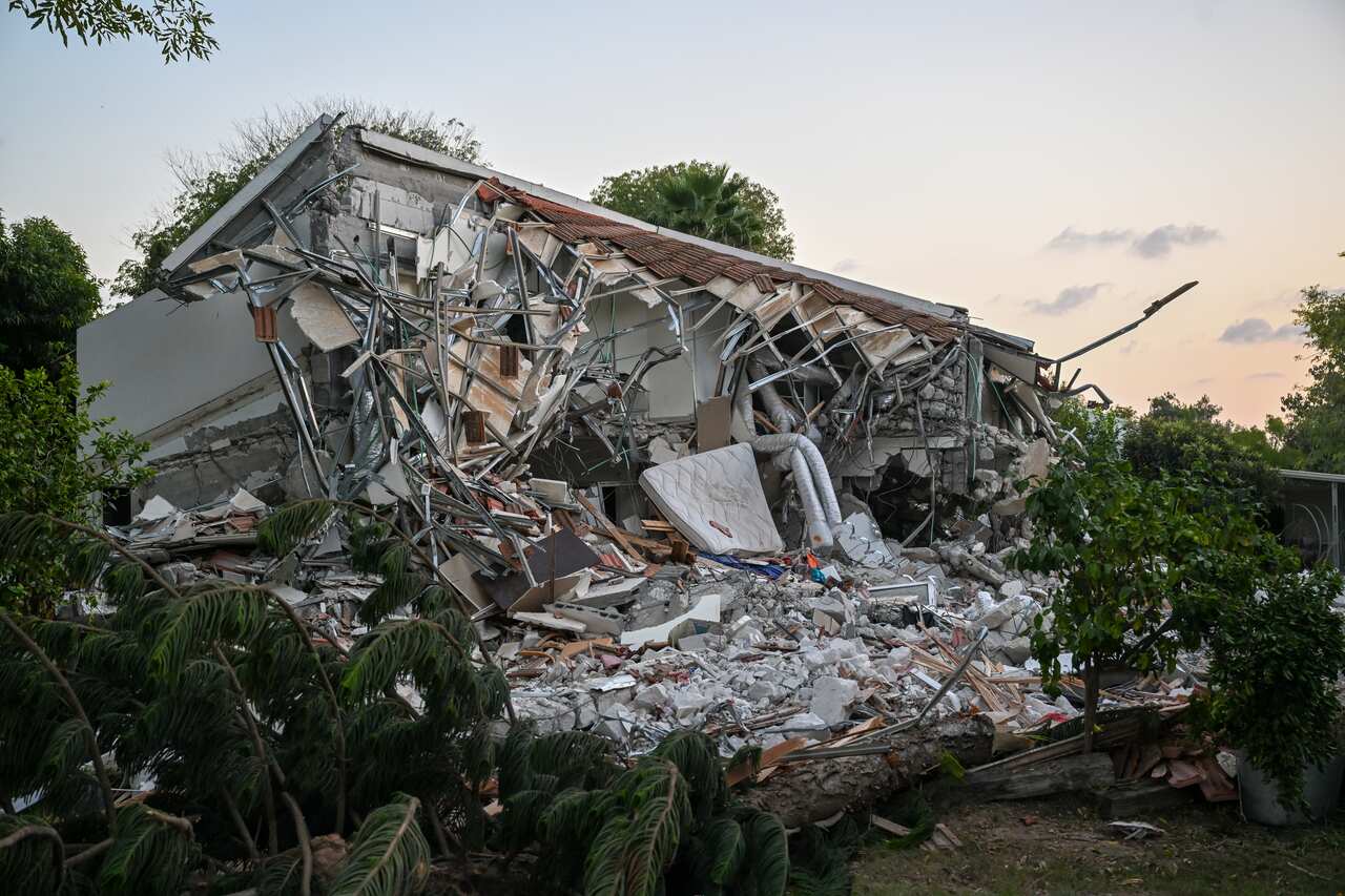 Disheveled building with rubble flowing out of it, including broken building parts and a mattress