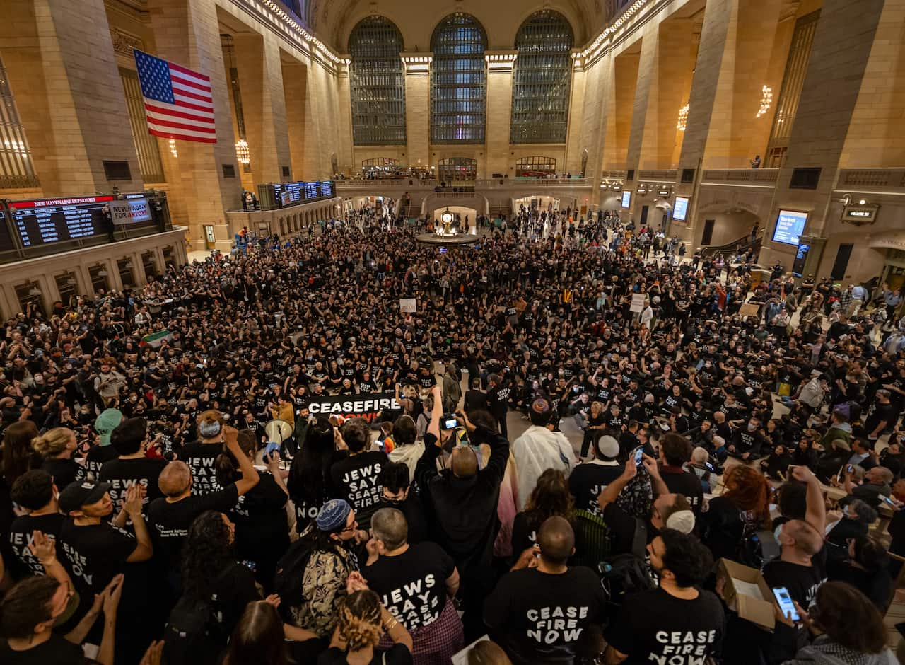 A large group of protesters rally in a train terminal.