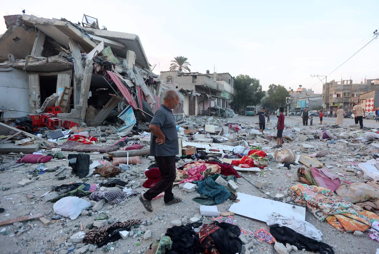 A man walking past a destroyed house.