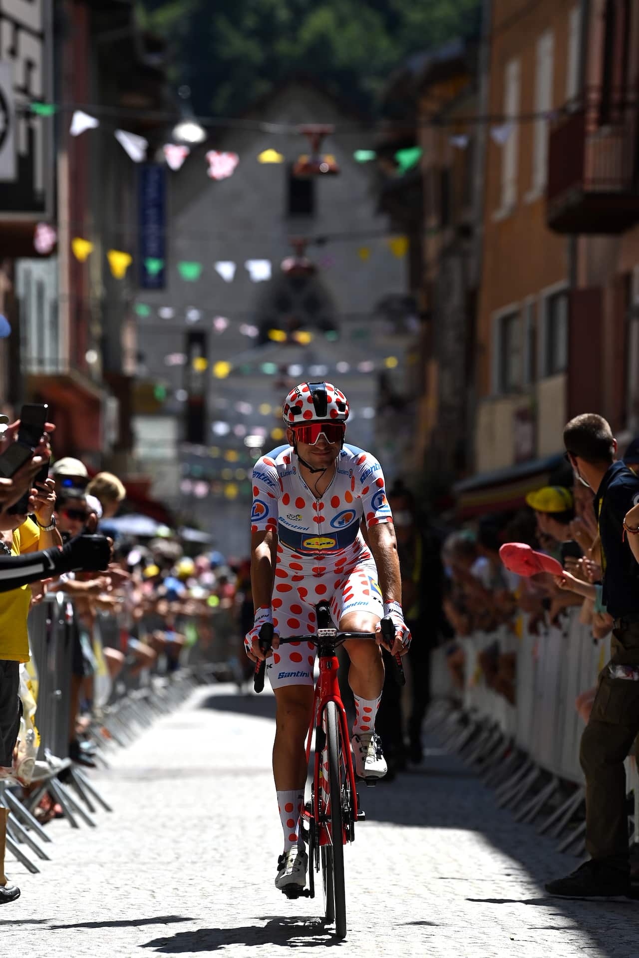 A man rides on a bike wearing a polka dot jersey.