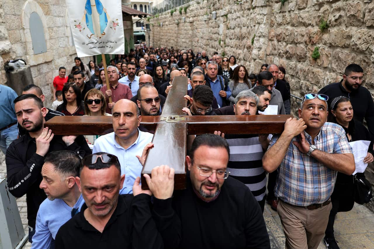 A group of men carry a large wooden cross on their shoulders during a Good Friday procession through the streets of the Old City of Jerusalem.
