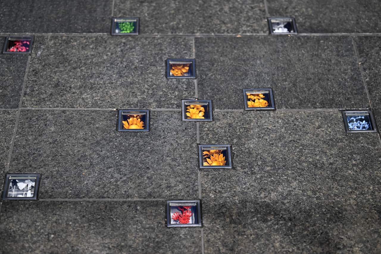 Small colourful flowers installed between paving tiles behind glass panes 