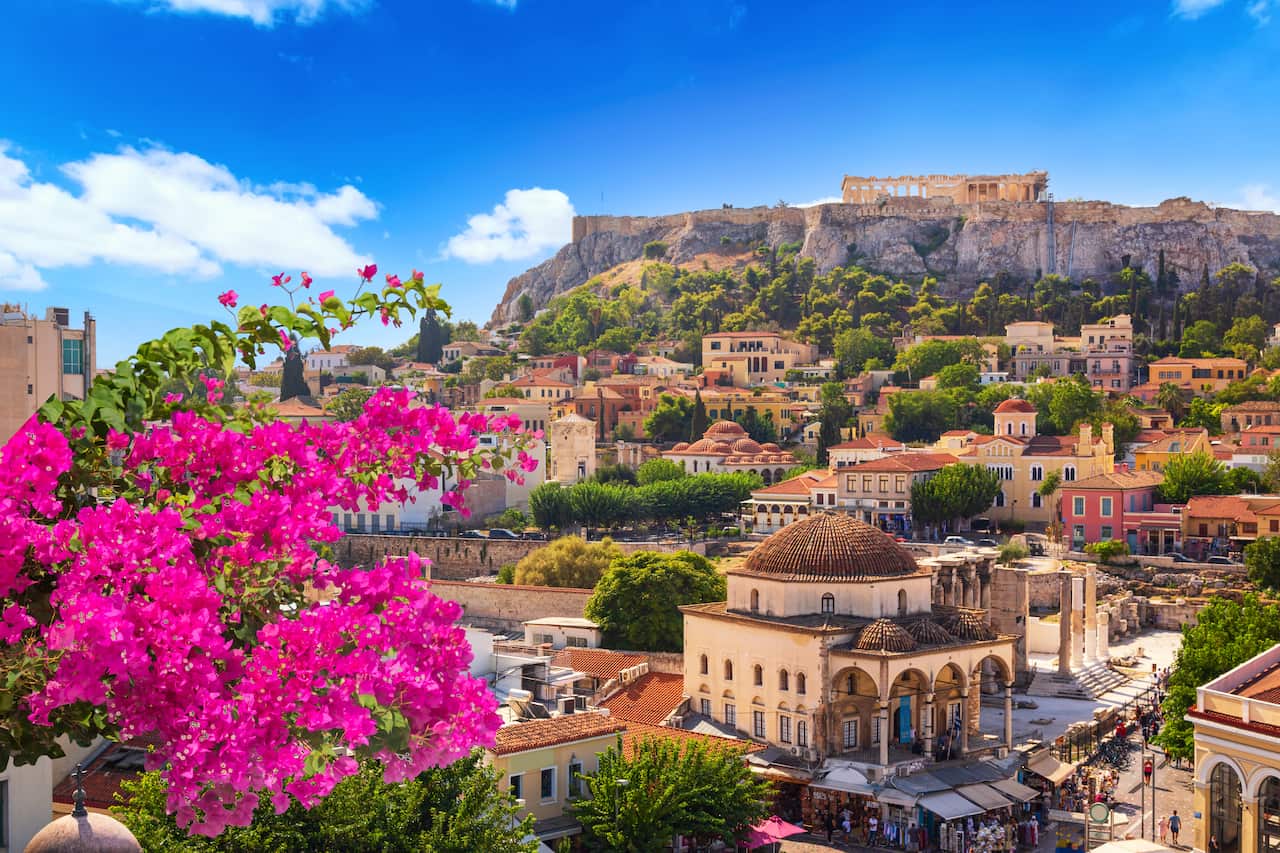 View of Athens including the Acropolis, with purple bougainvillea flowers in bloom. 