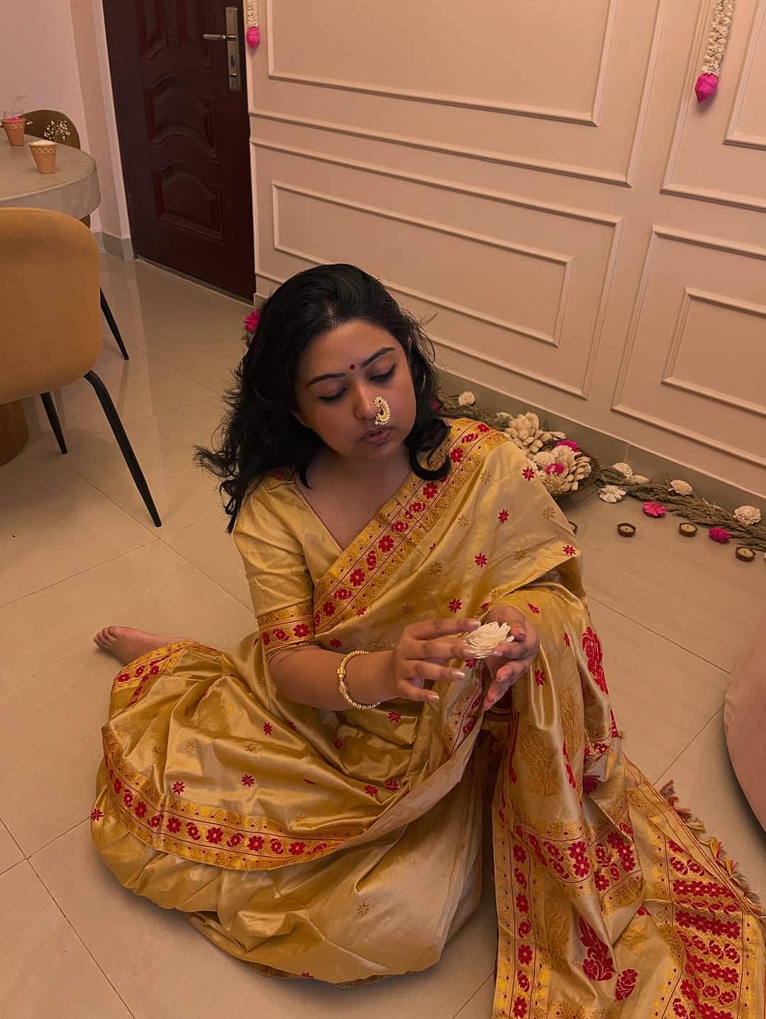 A woman wearing a traditional gown sitting on the floor. 