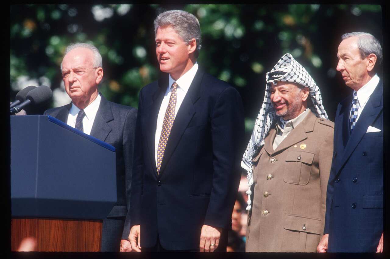 A group of men in suits stand behind a lectern.