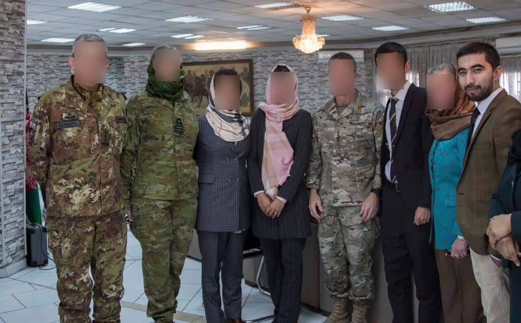 Naqib Forotan (right) stands inside next to seven other people, whose faces have been blurred.