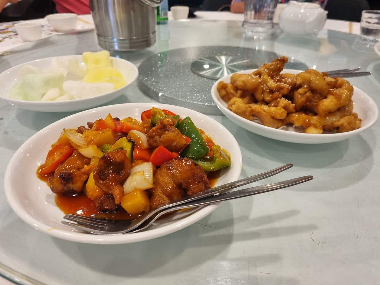 A lazy susan with dishes including sweet and sour pork and honey chicken on it.