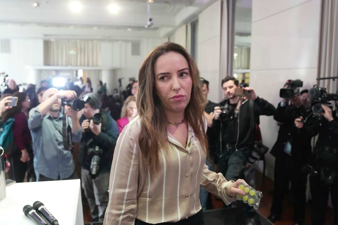 A woman walking while being photographed my news photographers.