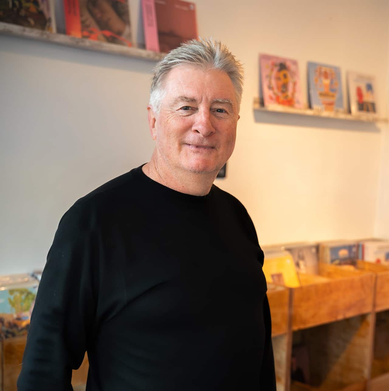 A man in a lack jumper standing in a record store.