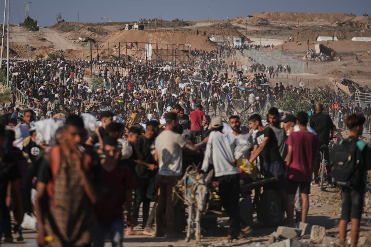 Palestinians carry humanitarian aid packages near a distribution center