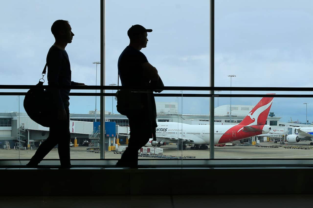 Two silhouetted people in front of a window at an airport.