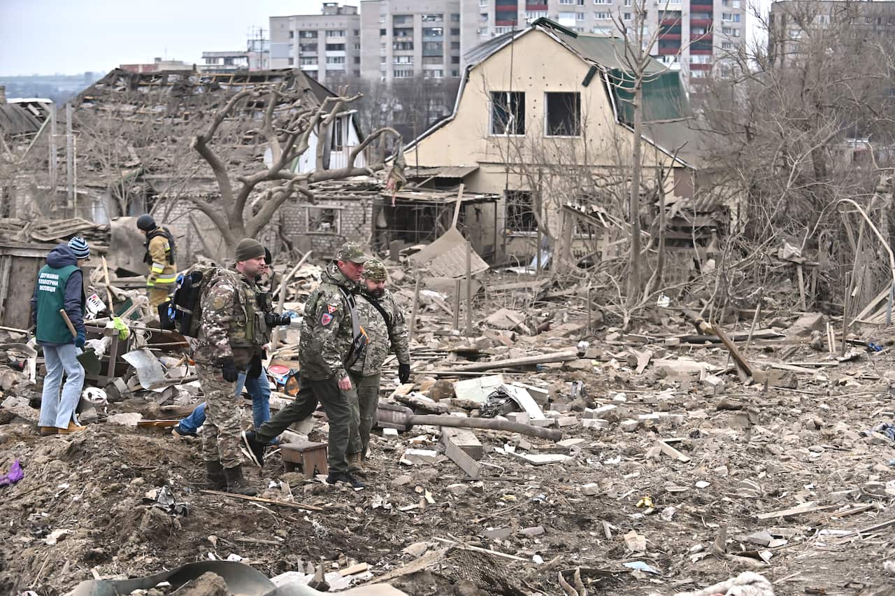 Soldiers walk among destroyed buildings and rubble