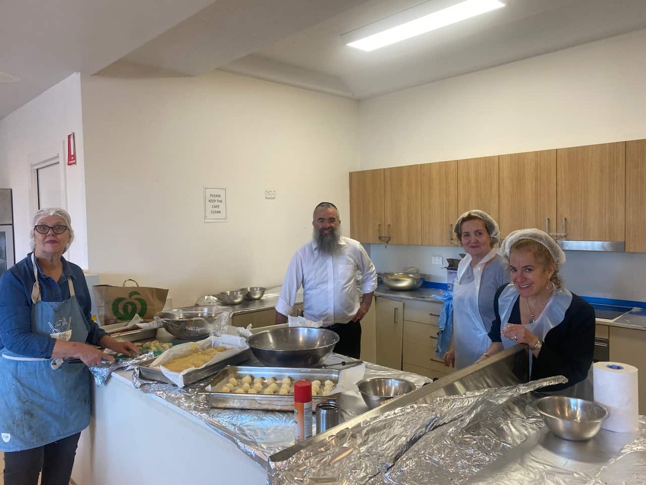 A group of people prepare food in bulk in a kitchen.