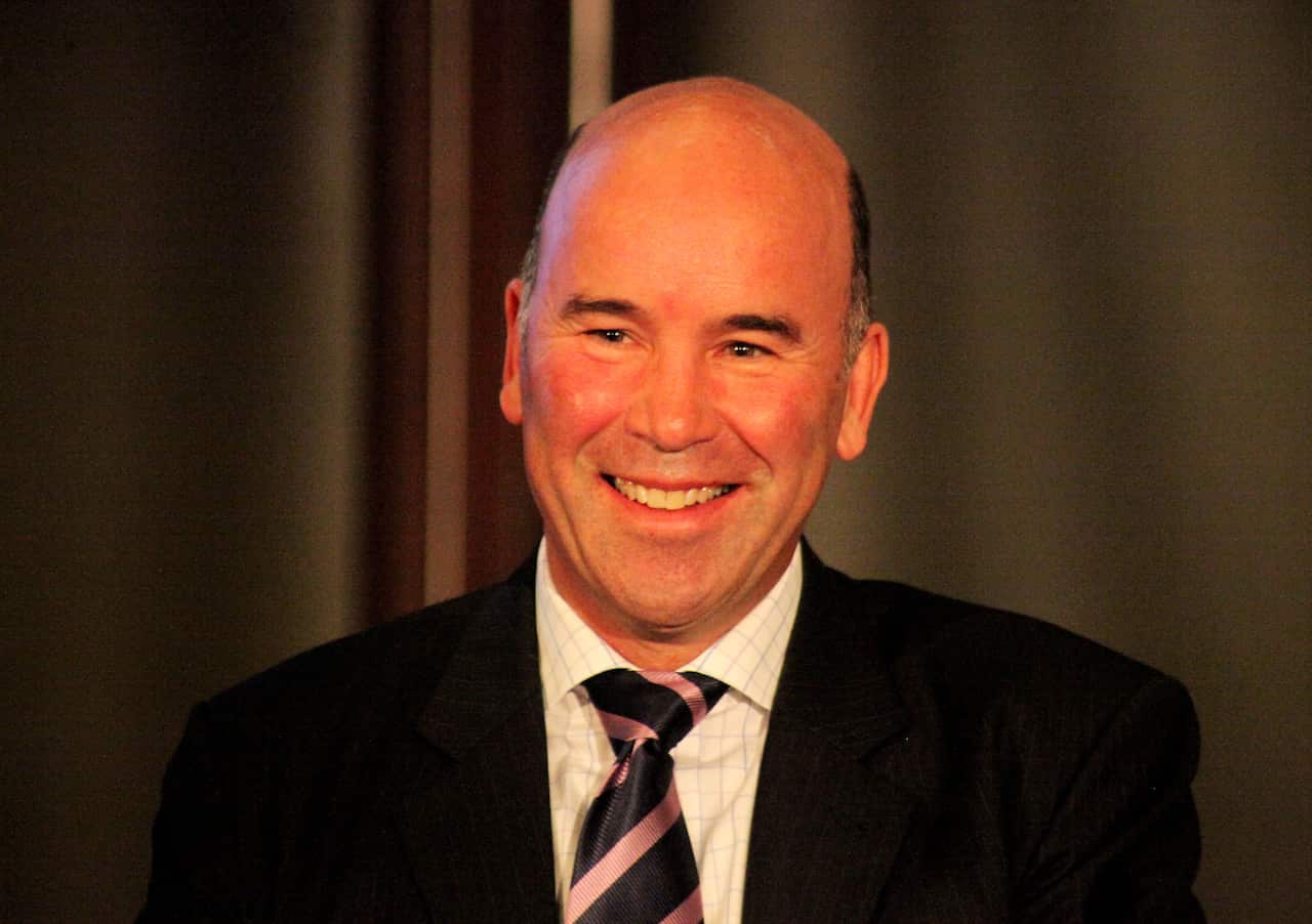 A smiling man, wearing a suit and tie.
