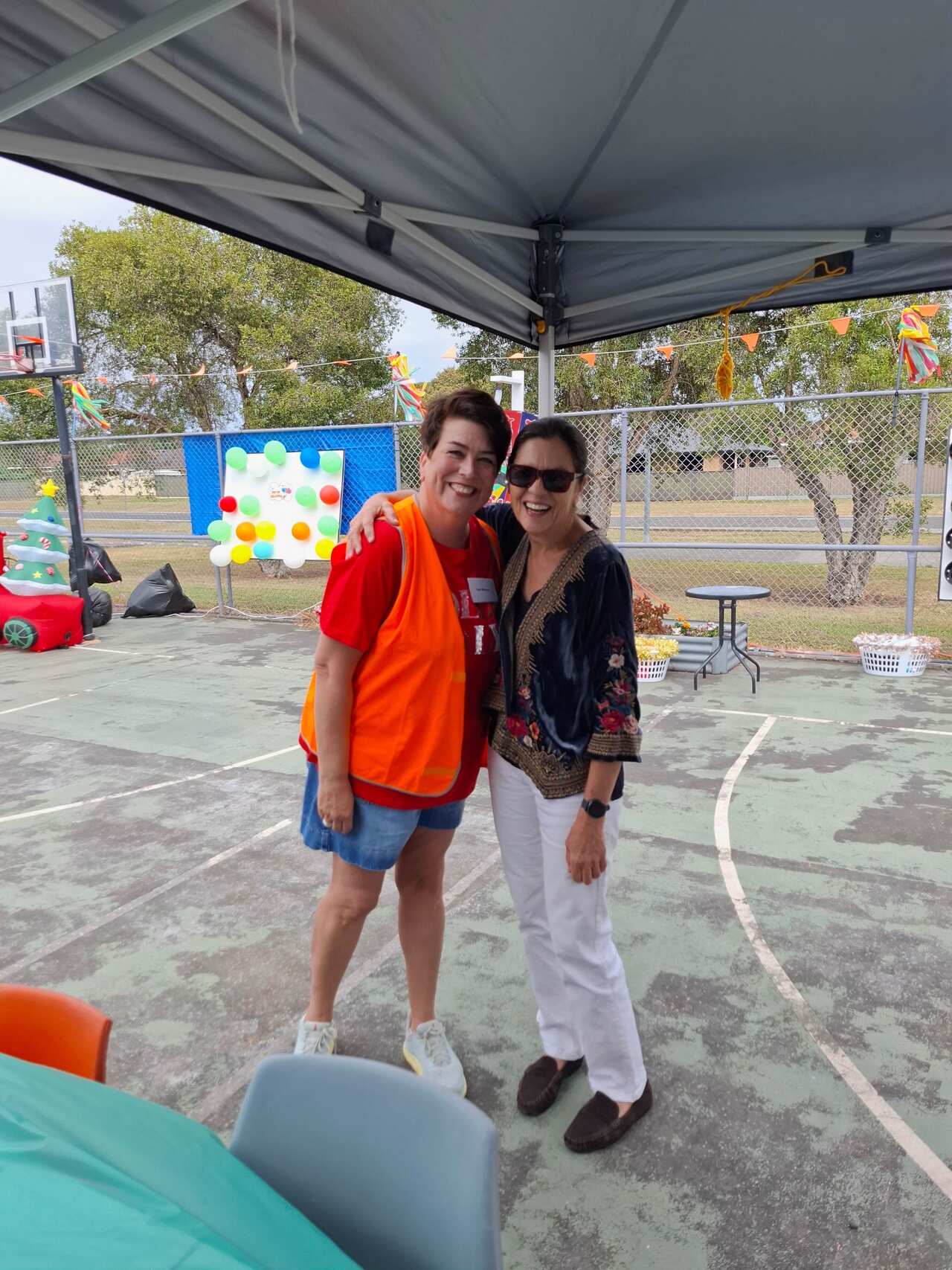 Two women smiling and posing on a basketball court.