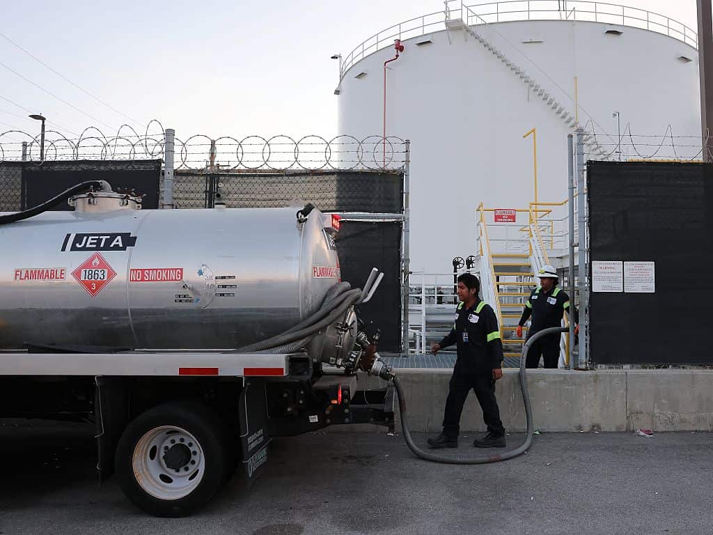 Workers fill up a jet fuel truck tank at a jet fuel station.