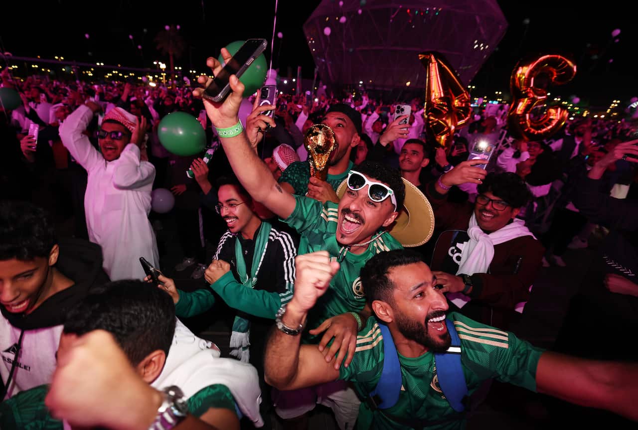 Crowds smile and celebrate while wearing football jerseys.