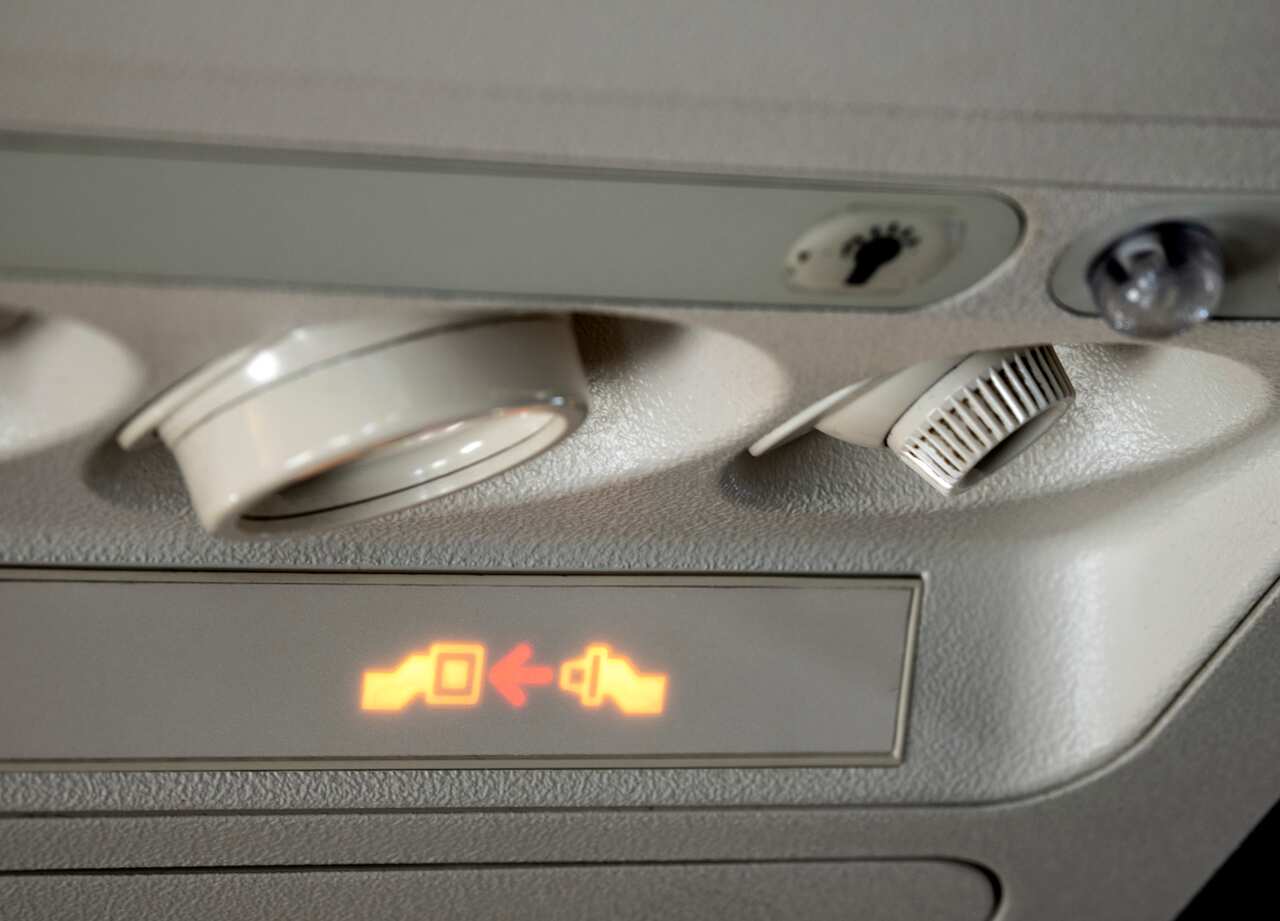 Safety sign in airplane, fasten seat belt.