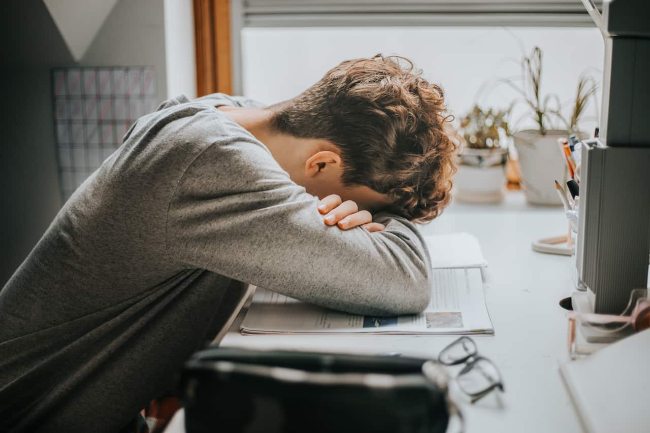 A man is sleeping at a desk.