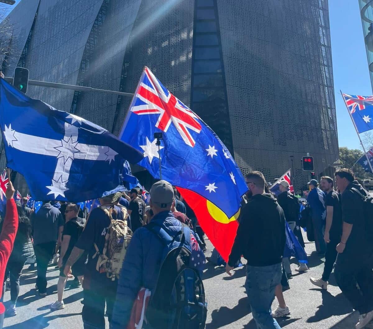 A group of people waving flags while marching down a road.