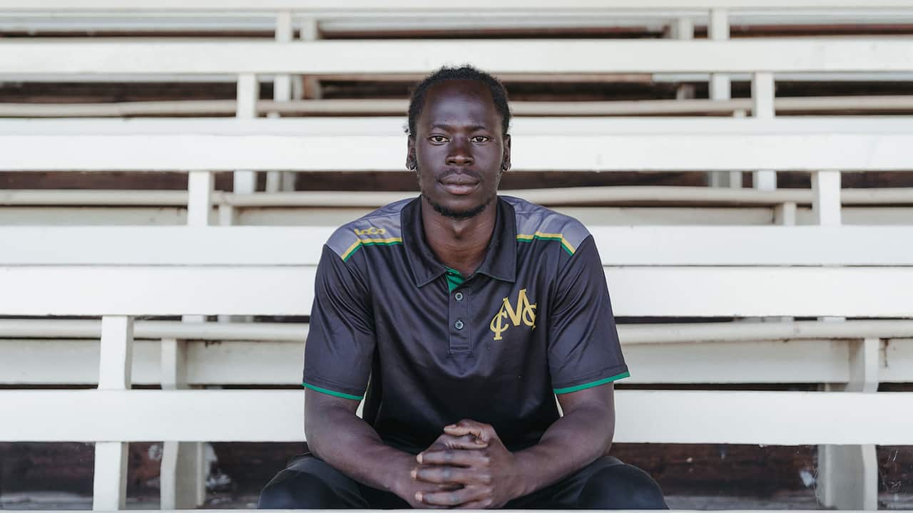 A young man sits in the stands of a sports stadium. 