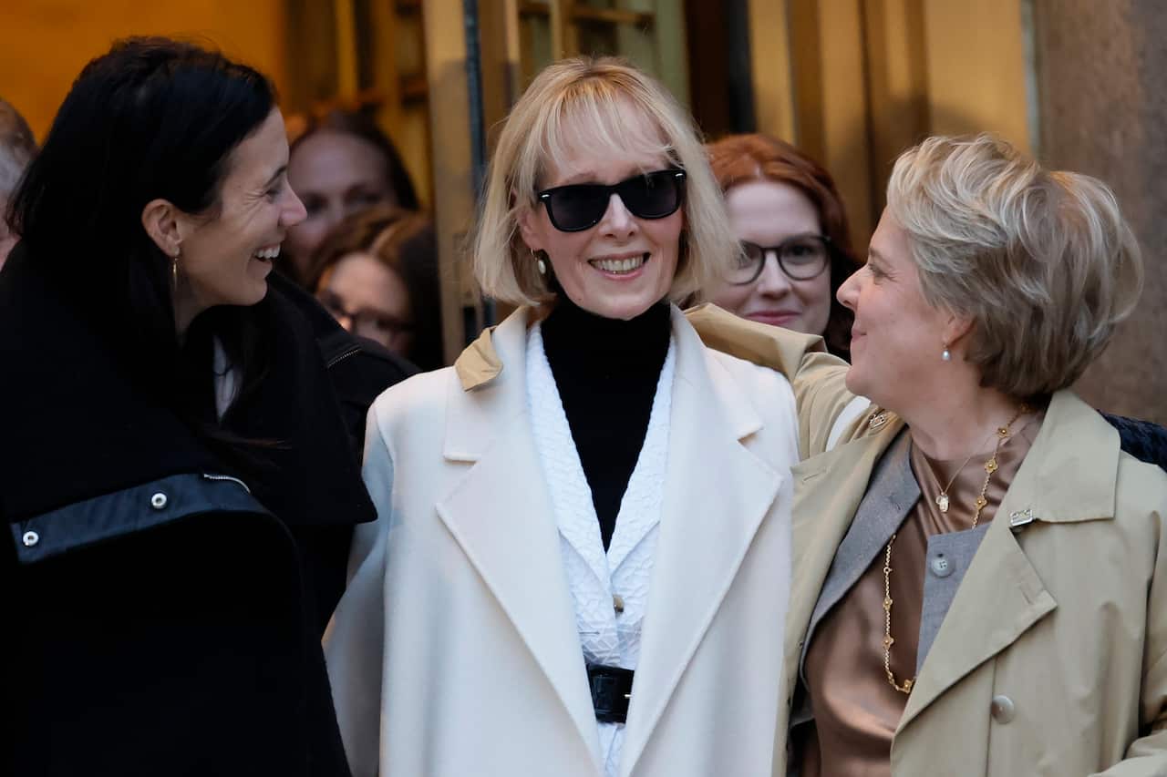 A woman in black sunglasses exiting a courtroom surrounded by other women.