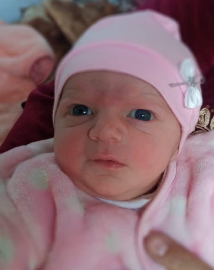 Baby wearing a pink onesie and hat.