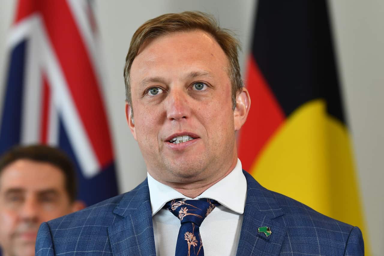 A man in a blue suit and printed tie speaks to the media.