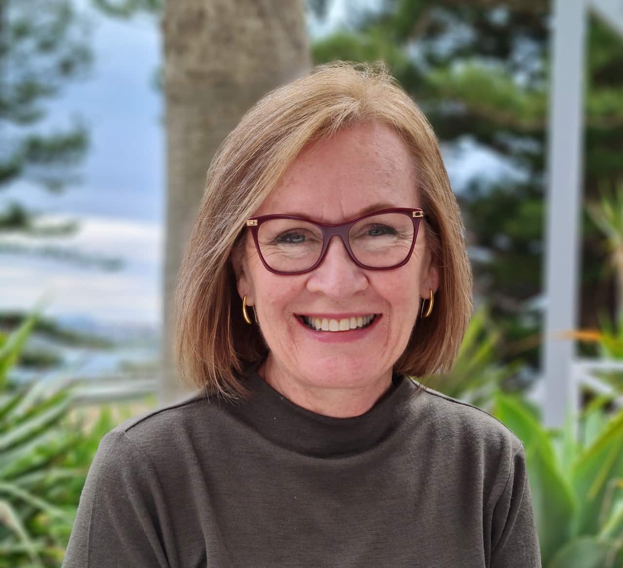 A woman with glasses and bobbed hair smiles at the camera.