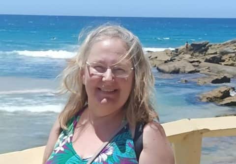 A woman standing with the oceans and rocks in the background