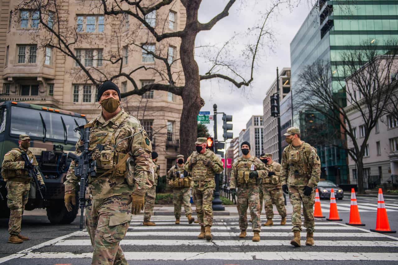 US national guard troops walking on a zebra crossing in a deserted street.