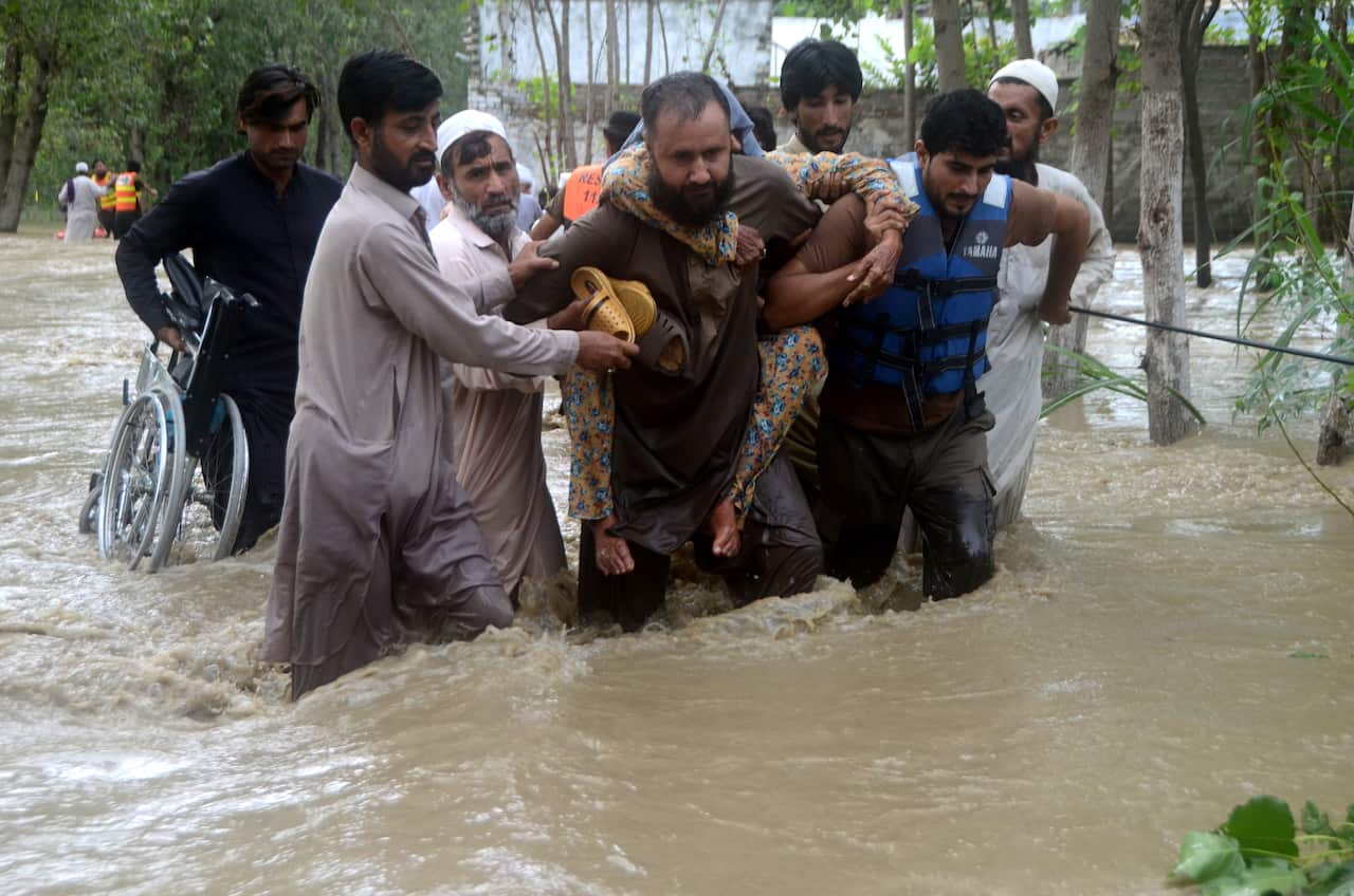 People carry each other out of heavy flooding. 