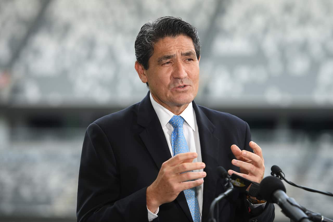 A man in a suit and blue tie talks on a microphone. 