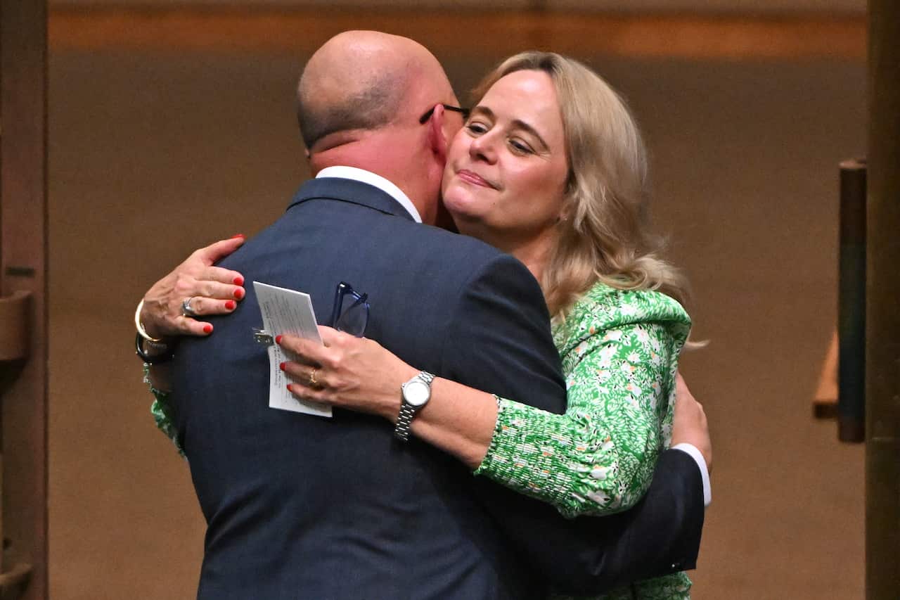 Man in suit embraces woman in green dress.