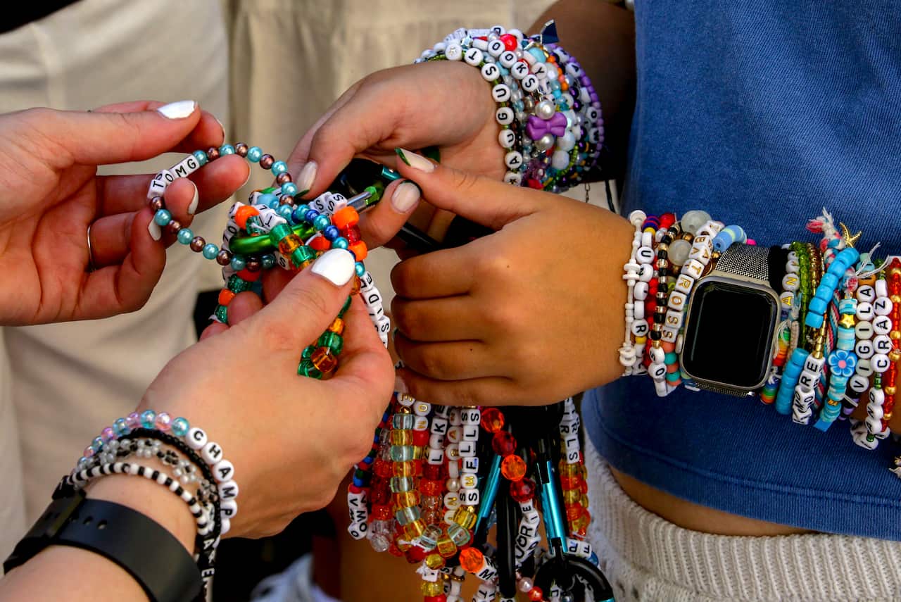People swapping colourful bracelets between their hands.