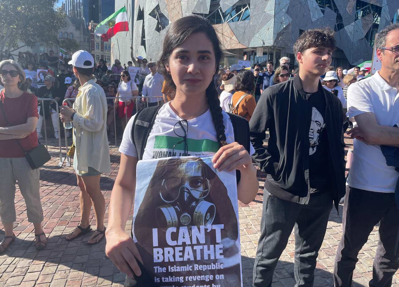 A woman in a white shirt holding up a protest sign that reads "I can't breathe".
