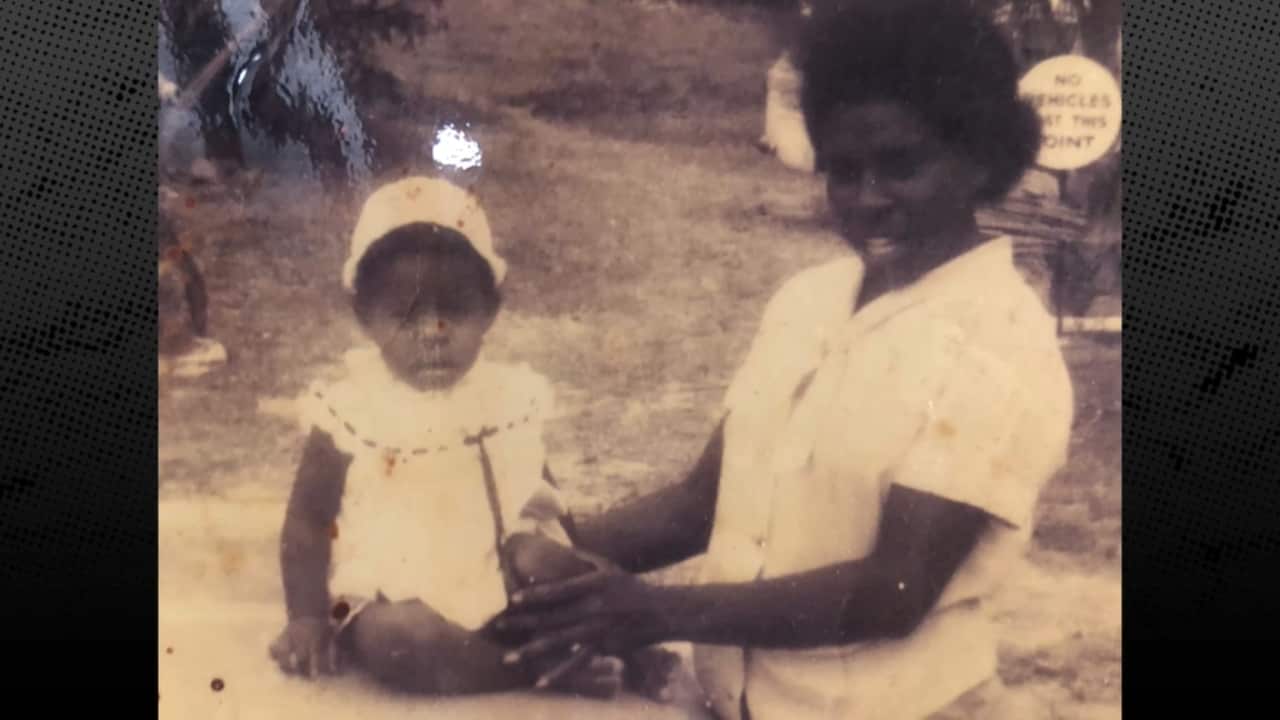 A black and white photograph of Deidree Whap when she was a baby, she is being held by her mother