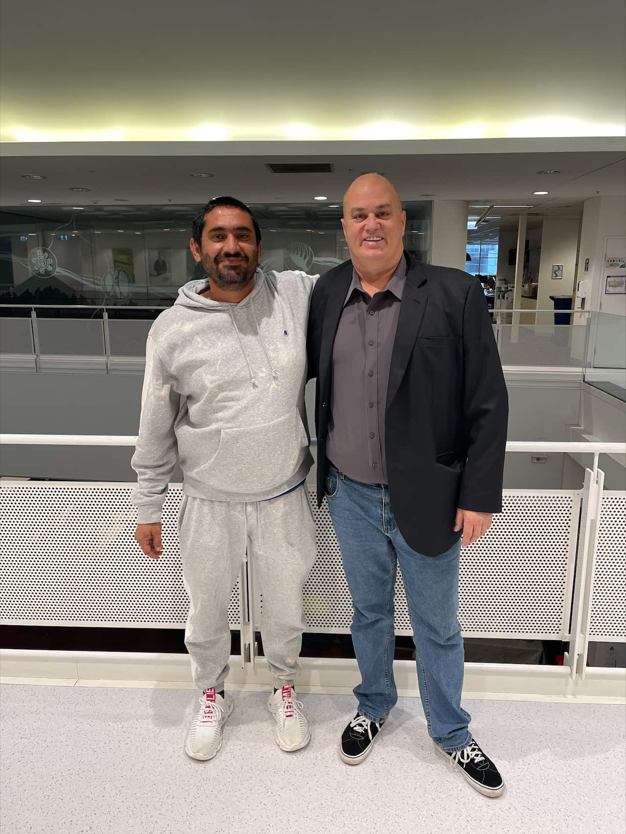 Warren and Najeeb with their arms around each other's shoulders.