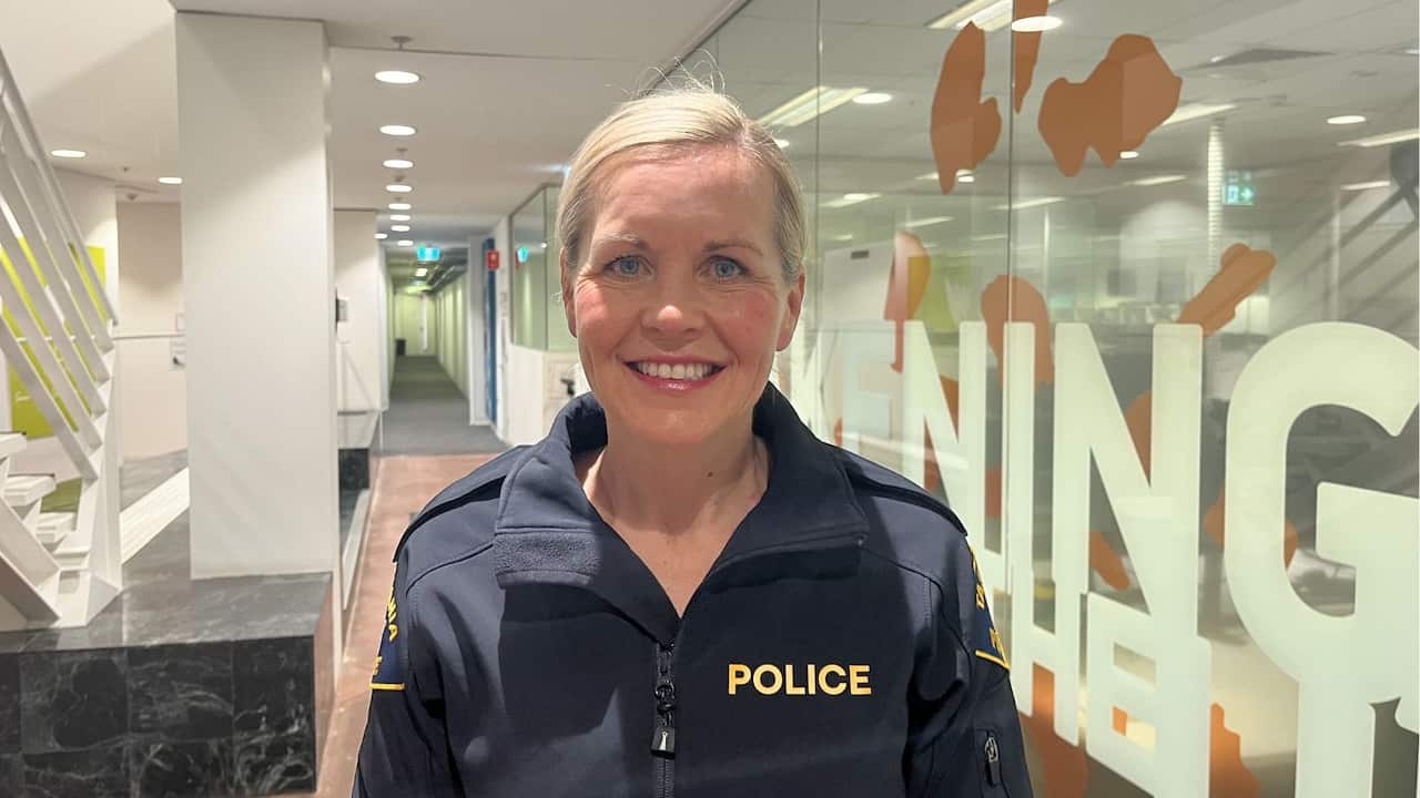a middle aged blonde police officer smiles in uniform in an office