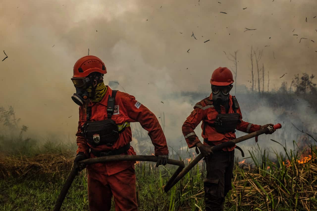 Two firefighters in masks in a smoky environment.