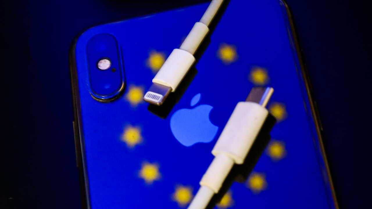 Apple iPhone laying face down in a case featuring the flag or Europe with USB-C and lightning charger on top of it
