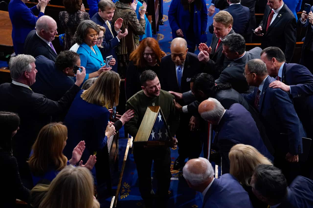 A man holds an American flag and receives a standing ovation as he leaves a meeting of Congress in Washington.