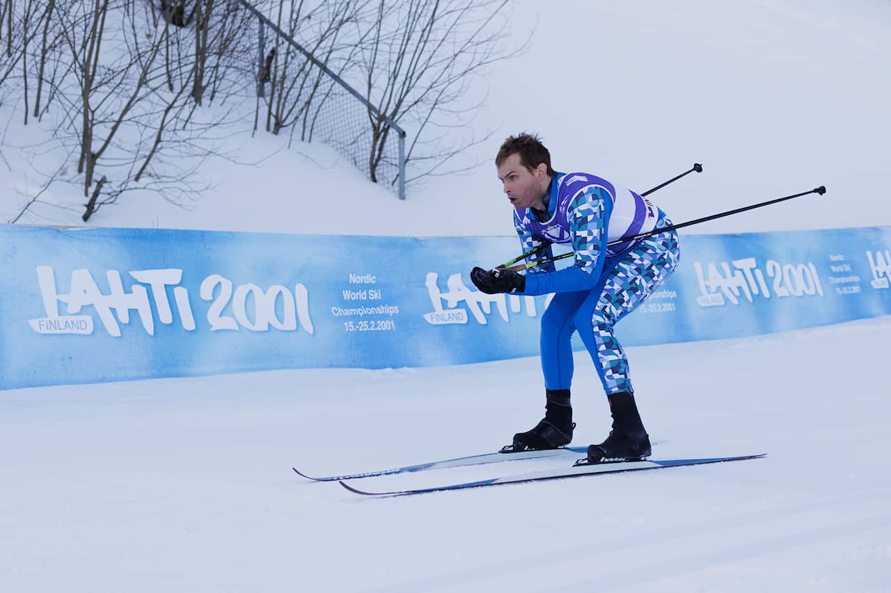 A man bends low, skiiing down a slope. Hoarding with the words Laiti 2001 can be seen behind him.