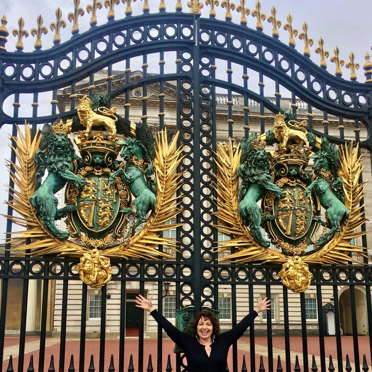 A woman standing in front of the gates of Buckingham Palace