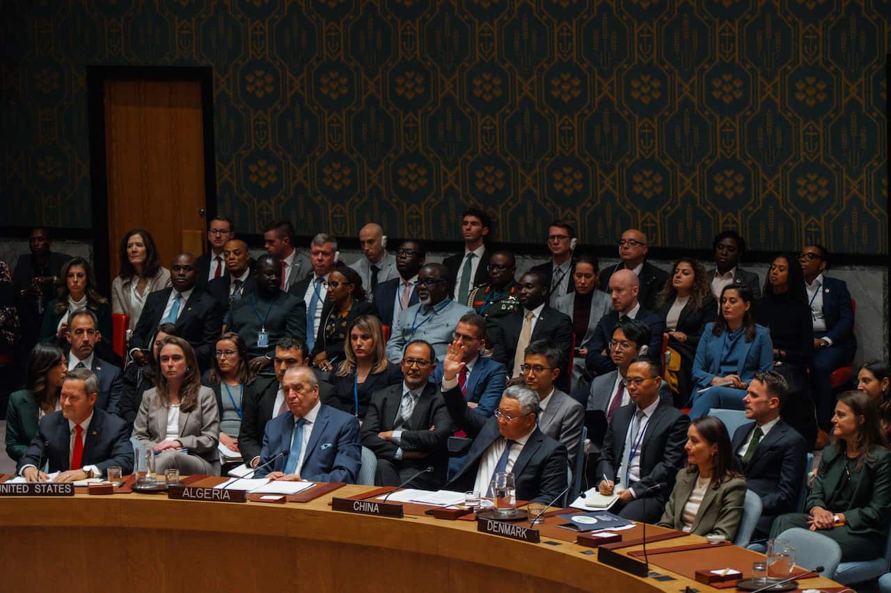 Several rows of people sitting down around a table.