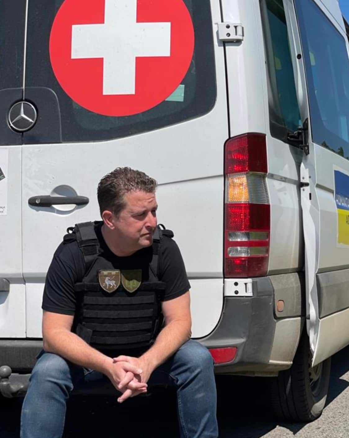 A man sitting on the rear bumper of an ambulance