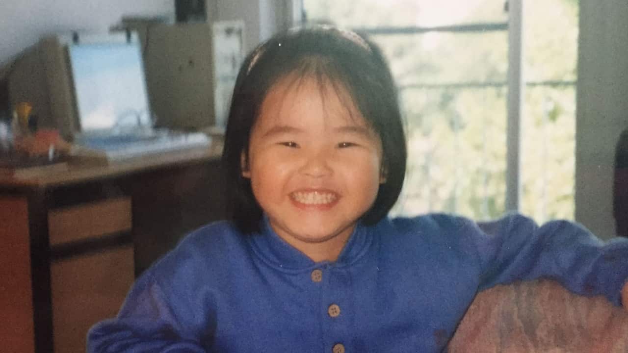 A young girl smiling for the camera in a home office