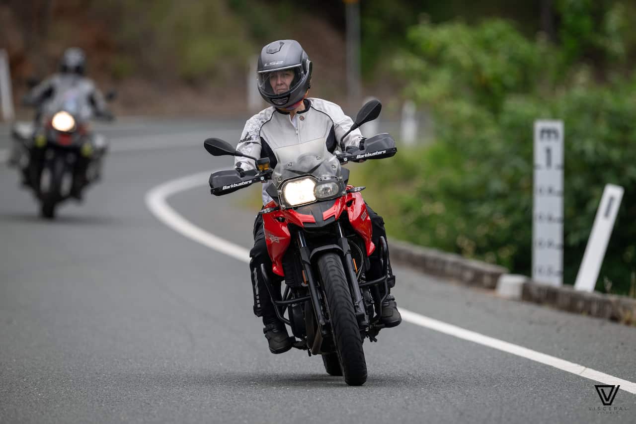 A woman rides a red motorbike