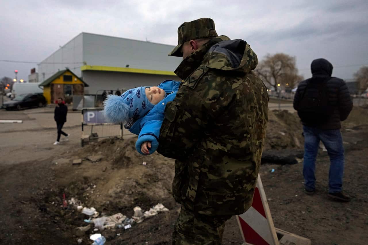 A Polish soldier carries a baby of a Ukrainian refugee upon their arrival at the border crossing in Medyka